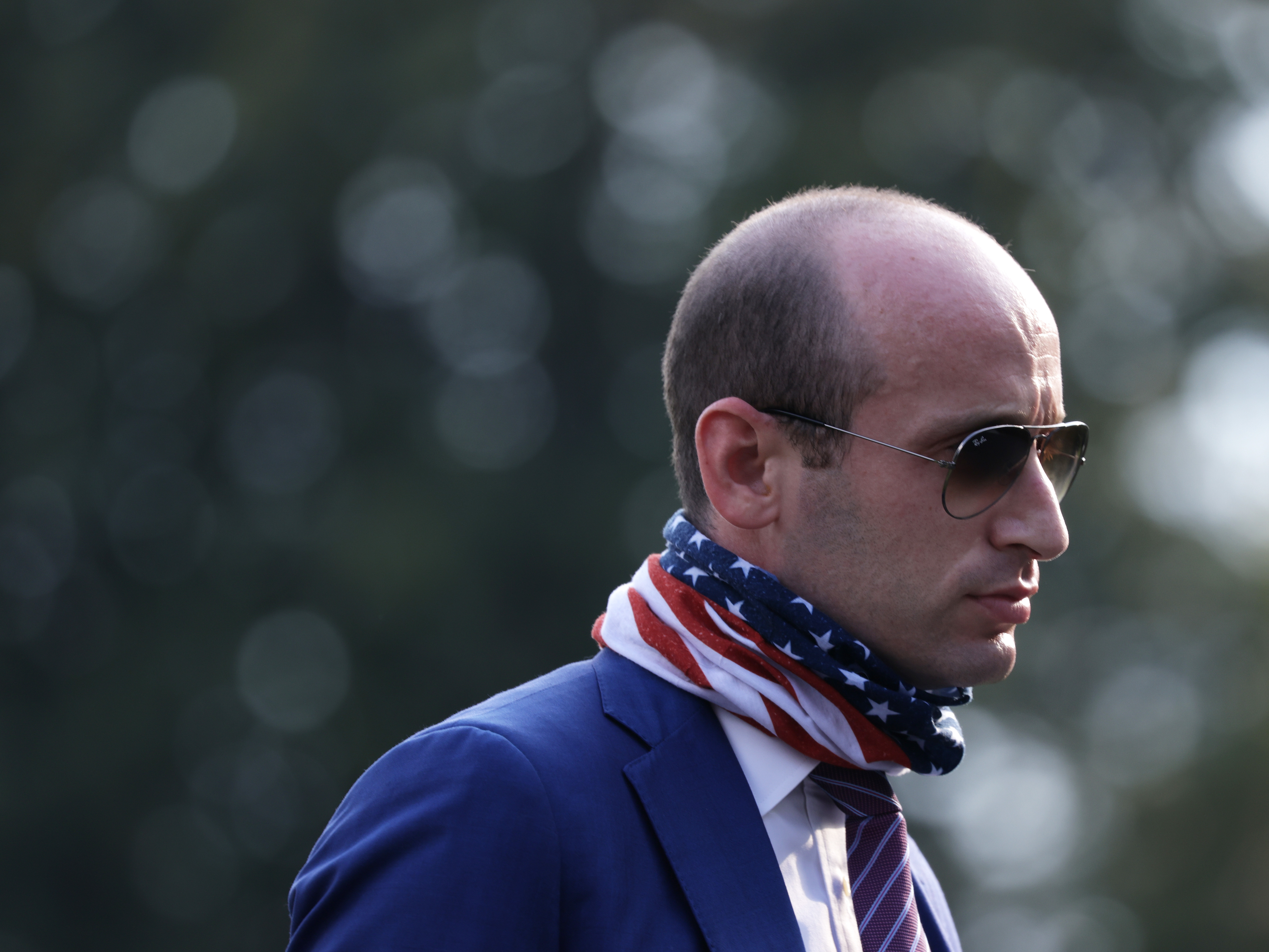 caption: Stephen Miller walks on the South Lawn of the White House in July after returning from a trip to Morrisville, N.C.