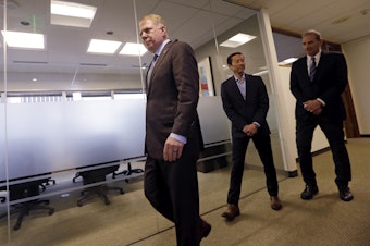 caption: Seattle Mayor Ed Murray, left, walks past his husband, Michael Shiosaki, center, and his attorney, Bob Sulkin, to make a statement to media members Friday, April 7, 2017, in Seattle. 
