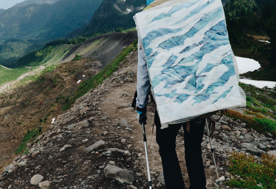 caption: Artist Claire Giordano carries all her materials with her on her expeditions, including a full canvas when needed.