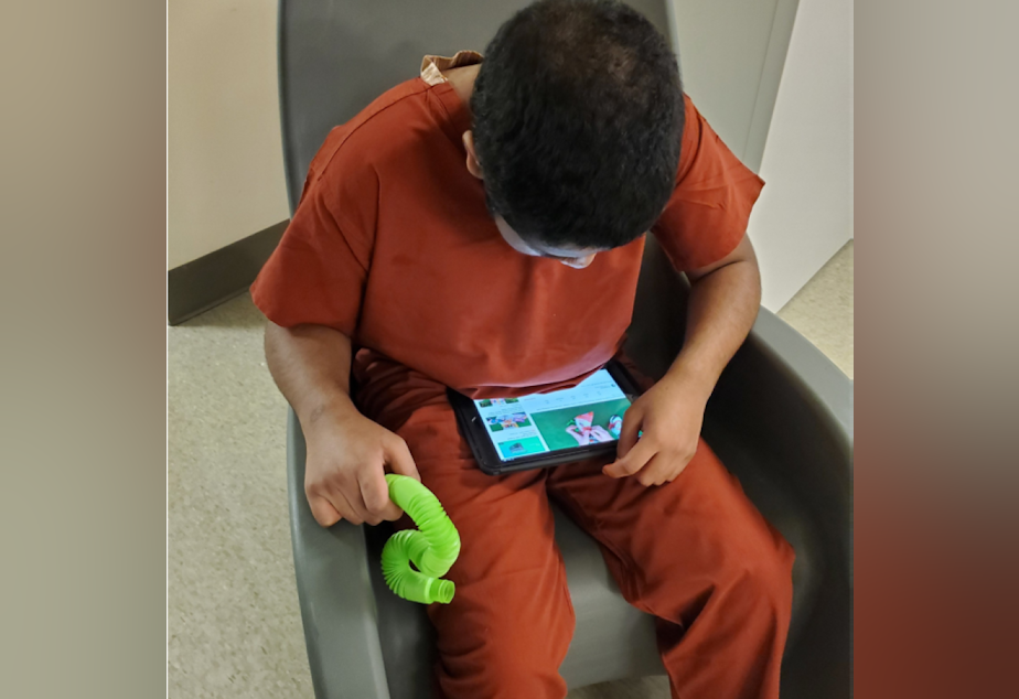 caption: Matthew, a 14-year-old who is autistic and nonverbal, watches YouTube and holds a fidget device. After being removed from his group home last September, Matthew was stuck in a hospital in Everett for more than five months while the state of Washington and advocates looked for appropriate placement options for him. He eventually ended up being sent to a treatment facility in South Carolina.