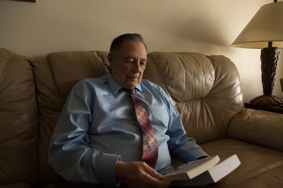 caption: Former Secret Service Agent Mike Endicott sits in his Tacoma home on January 18, 2020. He holds the two books he wrote on his life in the Secret Service. One of the books centered on Nixon's life after he resigned from office due to what infamously became known as Watergate.
