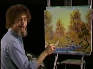 caption: A screenshot from the premiere of <em>The Joy of Painting</em> shows the painter Bob Ross with the work, A Walk in the Woods, which is up for sale.