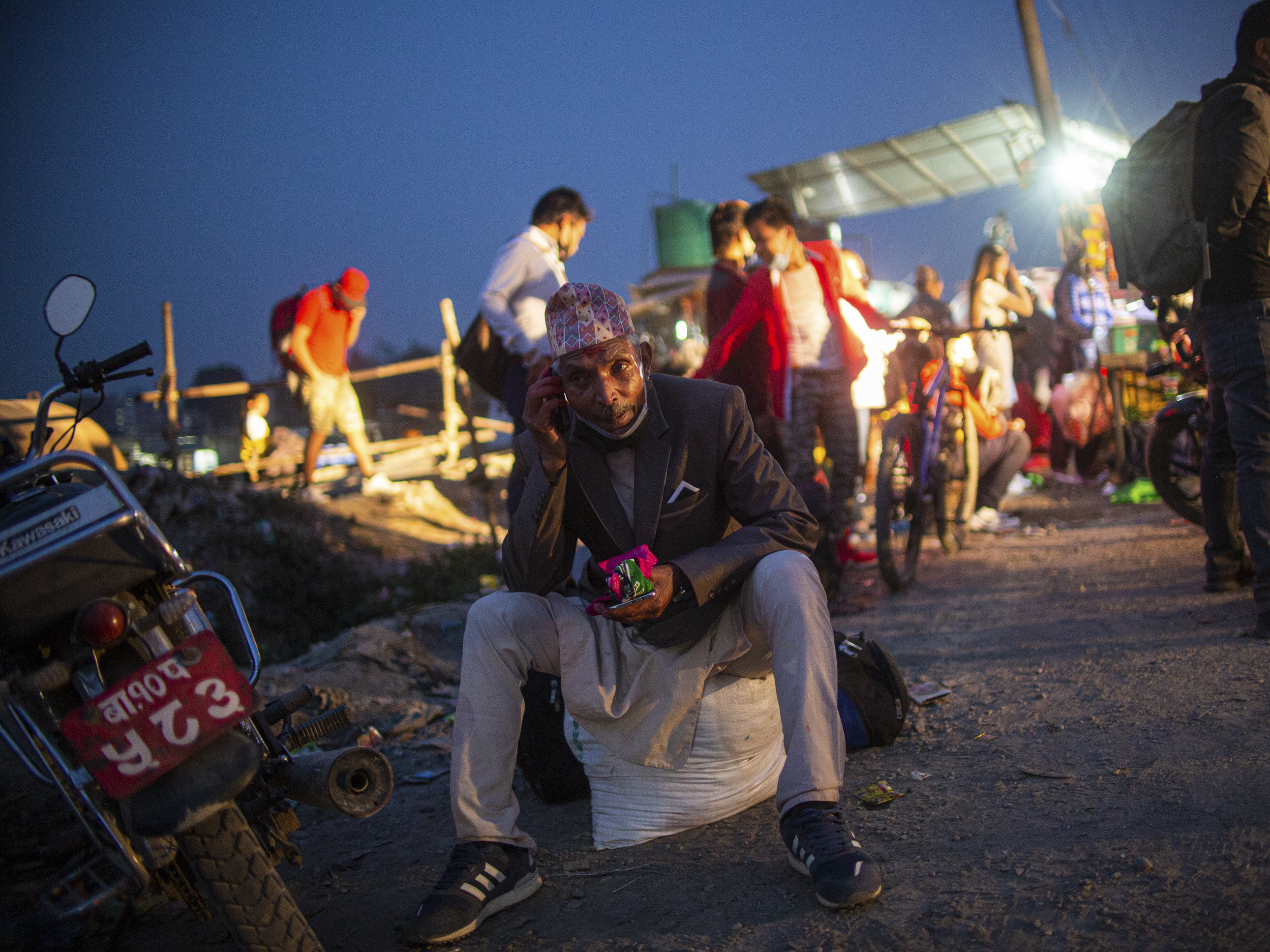 caption: Villagers wait to board a bus to head home in the wake of government-imposed restrictions relating to COVID-19 in Kathmandu valley.