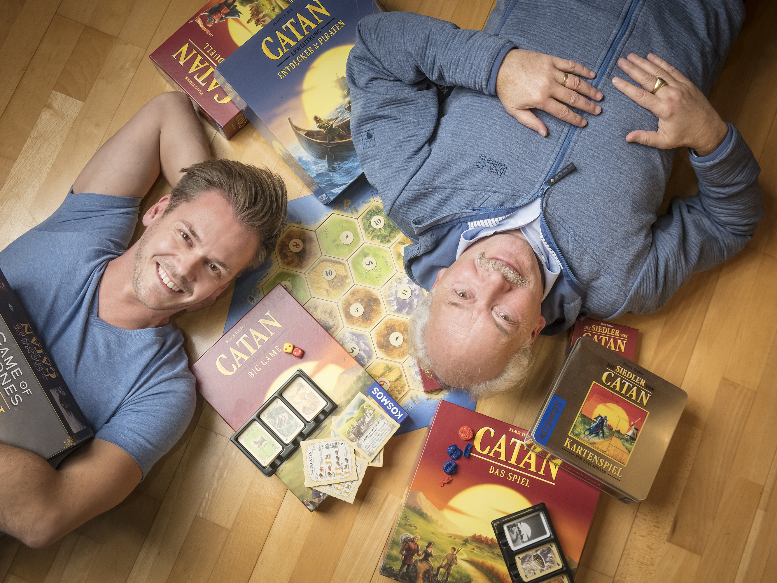 caption: Klaus Teuber, creator of the popular board game Settlers of Catan, with his son Benjamin Teuber, managing director of Catan Inc. As families shelter in place, the game's sales have skyrocketed. Celebrates the 25th anniversary since launch, the elder Teuber has released an autobiography, <em>My Way to Catan</em>.