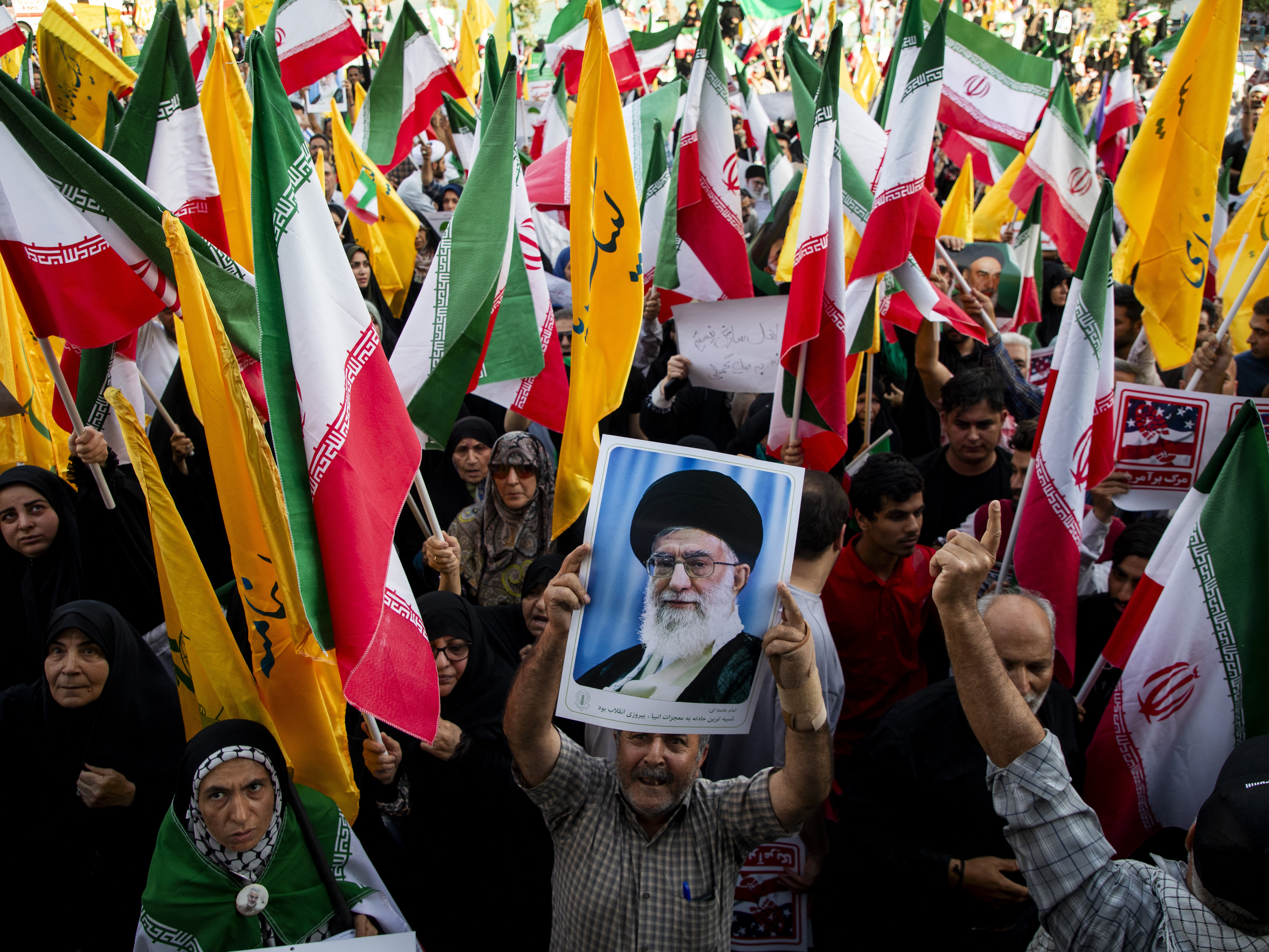 caption: People hold flags of Iran and Hezbollah as well as posters of Supreme Leader Khamenei as Iranians take to the streets in the downtown Enghelab (Revolution) Square in Tehran, Iran on June 24, 2025, to celebrate the ceasefire after a 12-day war with Israel.