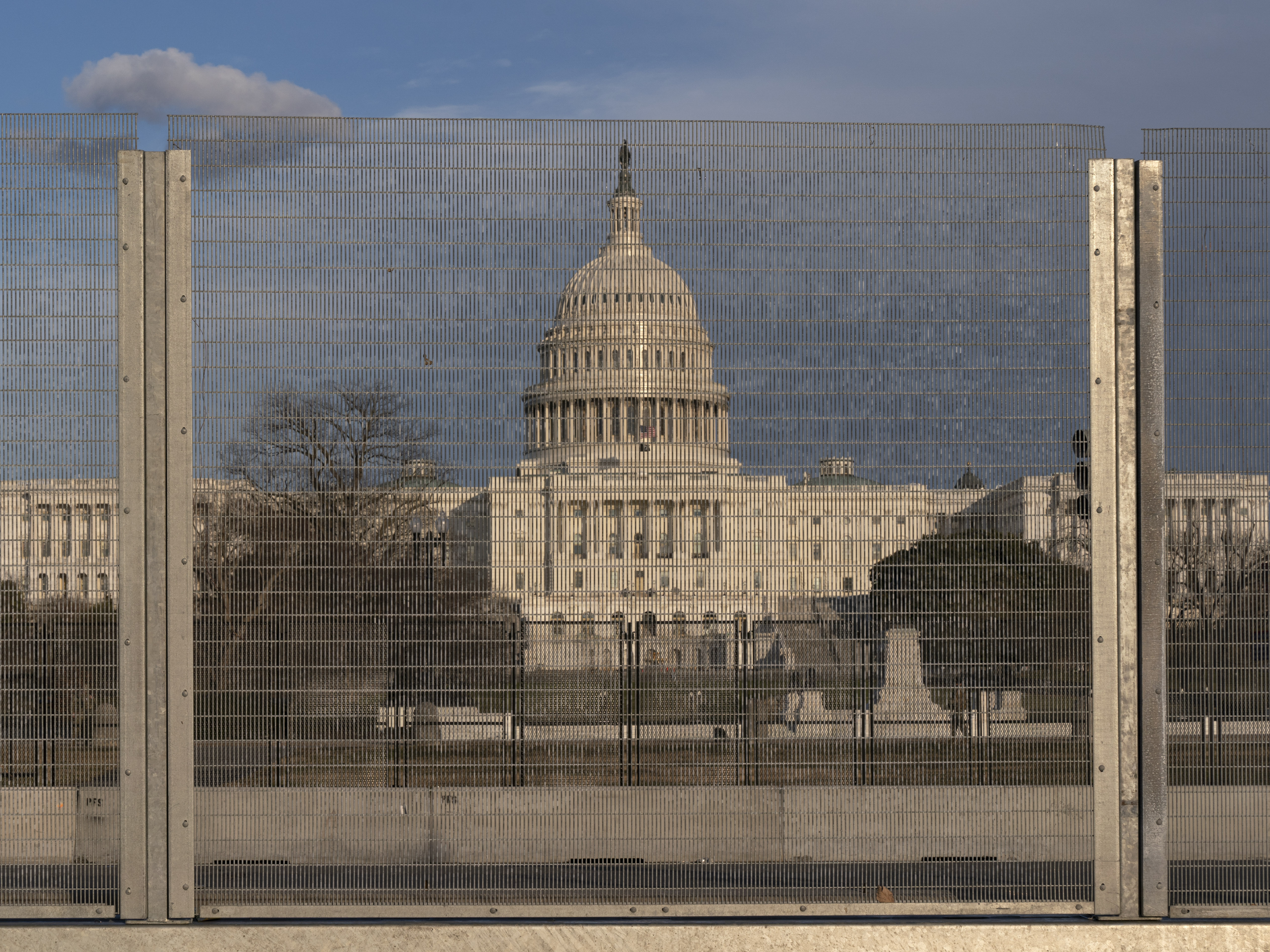 caption: A section of fencing blocking the Capitol grounds is seen at sunset Monday.