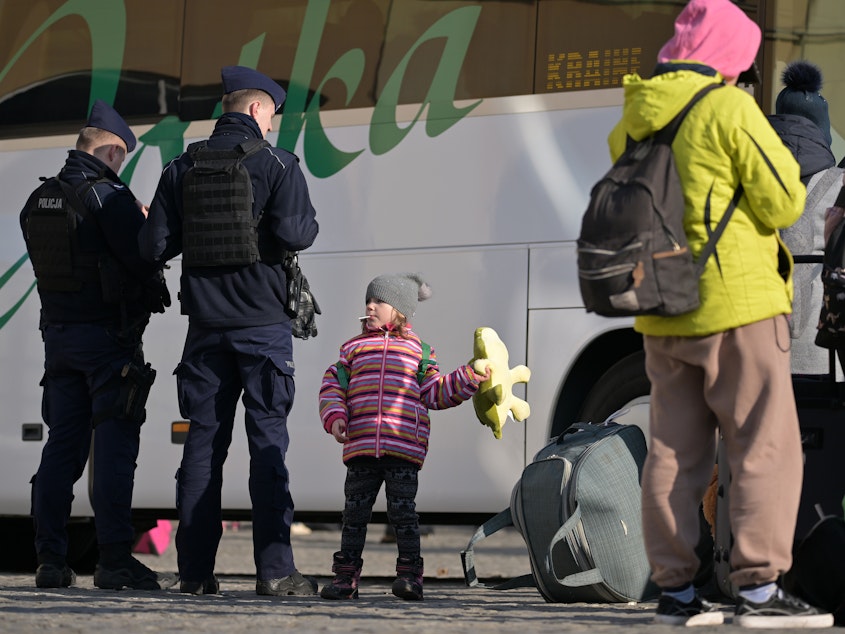 caption: People pass through Przemysl station in Poland on their journey out of war-torn Ukraine on Thursday. One in four Ukrainians have been displaced from their homes in the past month.