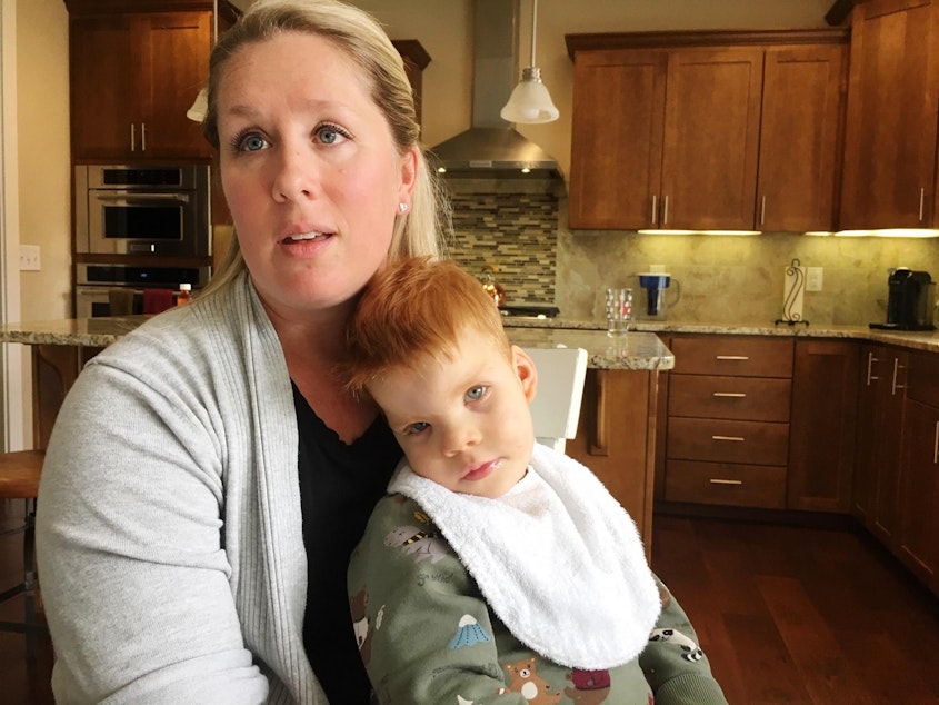 caption: Lindsey Topping-Schuetz holds her nearly three-year-old son Owen who qualifies for developmental disabilities services, but has been denied them because of a lack of state funding.

