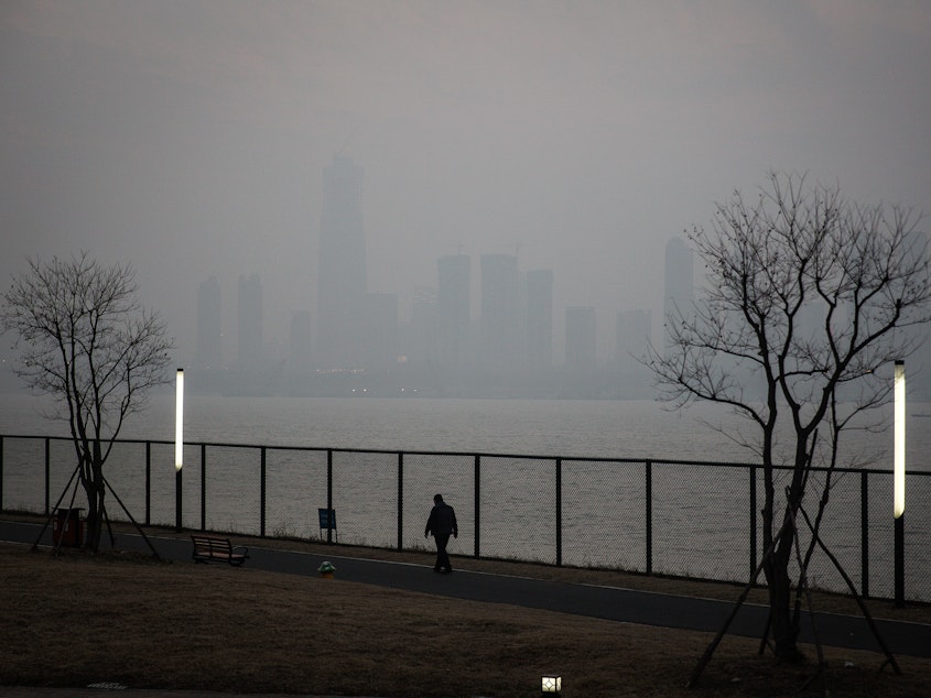 caption: A man walks along the Yangtze River in Wuhan, the city in China where the novel coronavirus was first identified.
