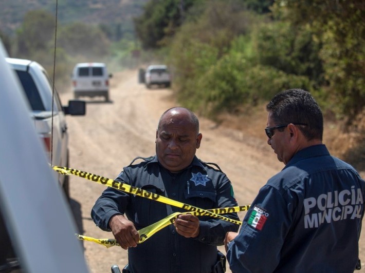 caption: Officers hold a police cordon at the scene where two young American children were found dead in Rosarito, Baja California state, Mexico, on Monday.
