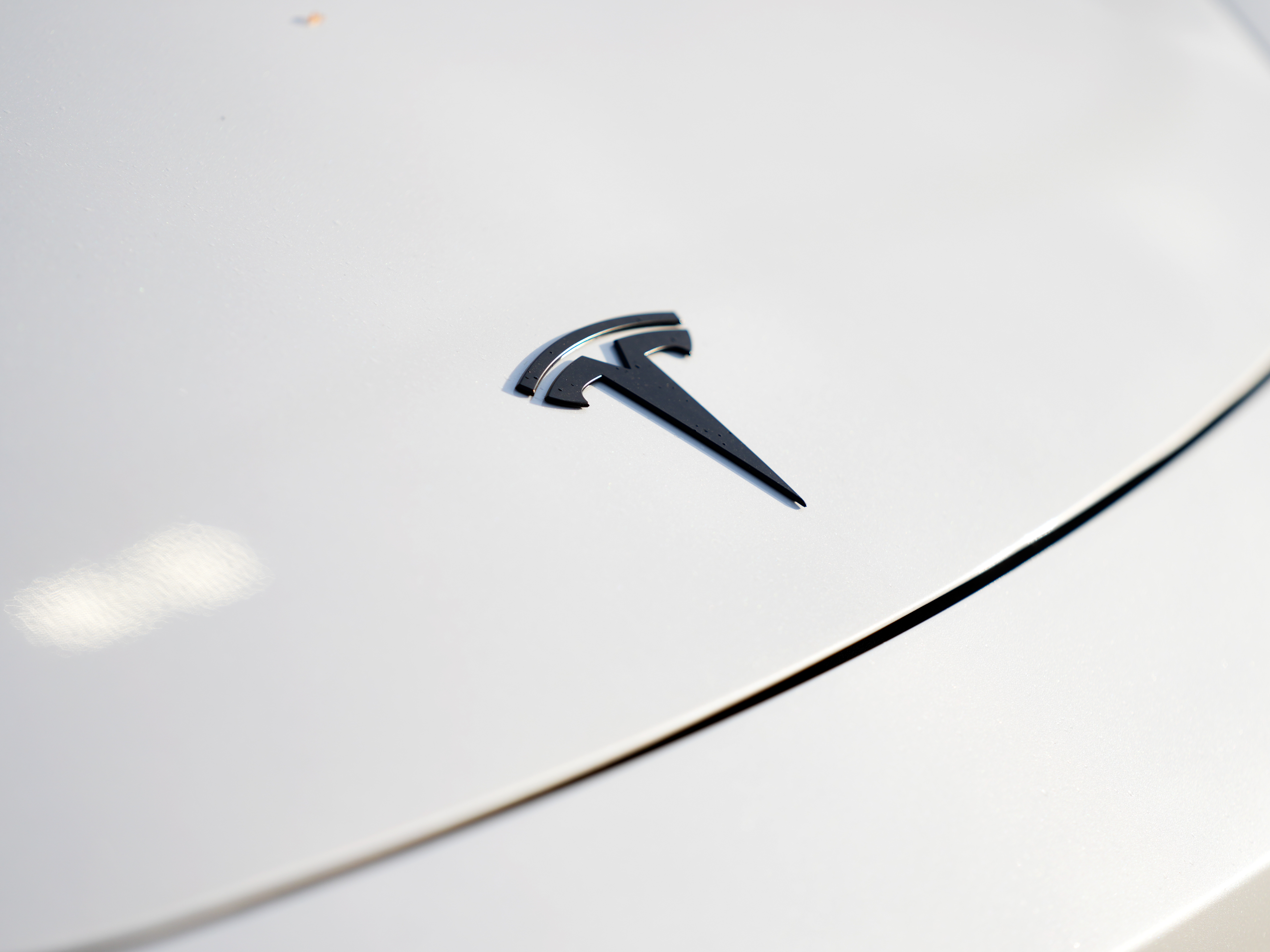 caption: A logo for Tesla is seen on a vehicle at a Tesla facility Wednesday, April 15, 2026, in Portland, Ore.