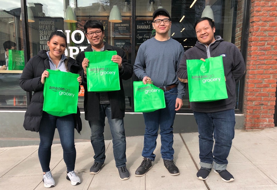 caption: Adam Thavixay (center right) and his coworkers dropped by Amazon Go Grocery around lunch time on its opening day of February 25, 2020.