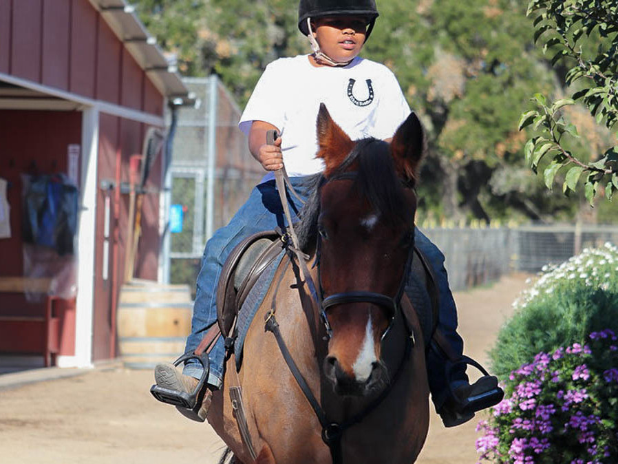 caption: Jordan Humpreys seen riding his horse Winter at the Urban Saddles stables, in South Gate, Los Angeles.
