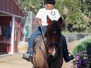 caption: Jordan Humpreys seen riding his horse Winter at the Urban Saddles stables, in South Gate, Los Angeles.