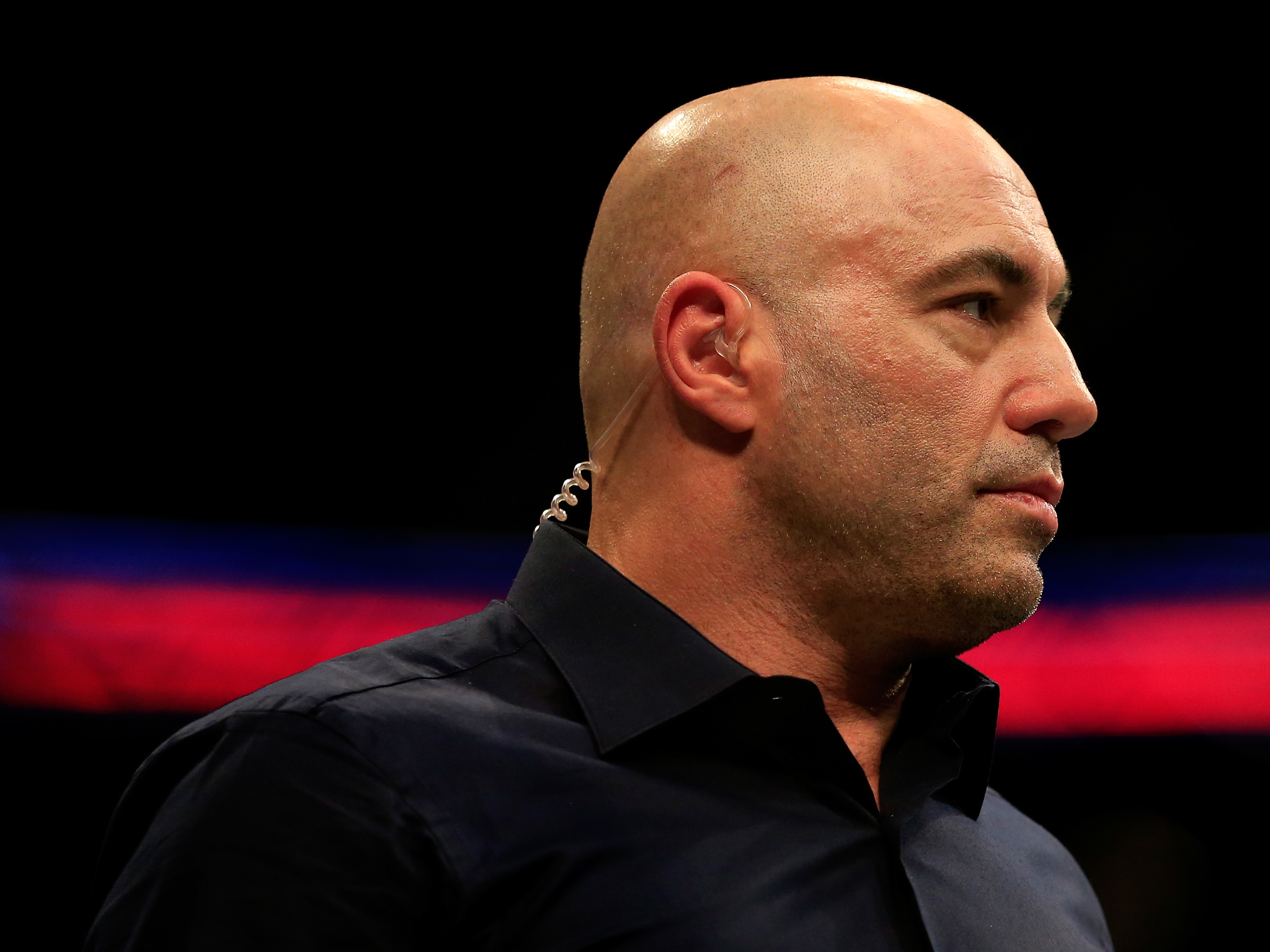 caption: Podcaster and comic Joe Rogan, who also serves as a mixed martial arts commentator, looks on at a UFC fight in 2015.