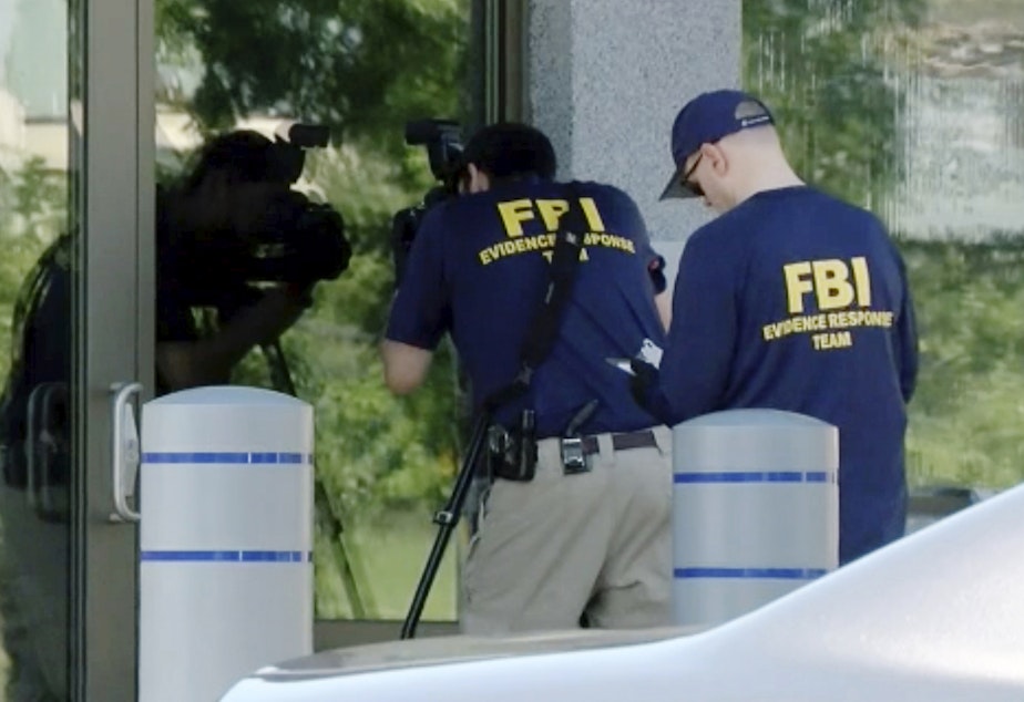 caption: FBI agents document evidence outside a bureau field office in Kenwood, Ohio, on Aug. 11, after an armed man tried to breach the building. He fled and was later killed by law enforcement, authorities said.