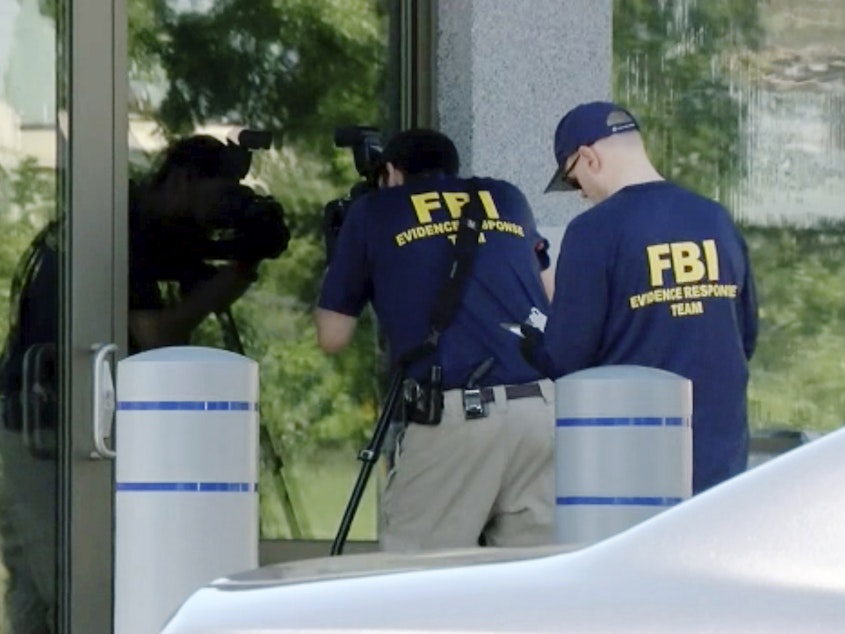 caption: FBI agents document evidence outside a bureau field office in Kenwood, Ohio, on Aug. 11, after an armed man tried to breach the building. He fled and was later killed by law enforcement, authorities said.