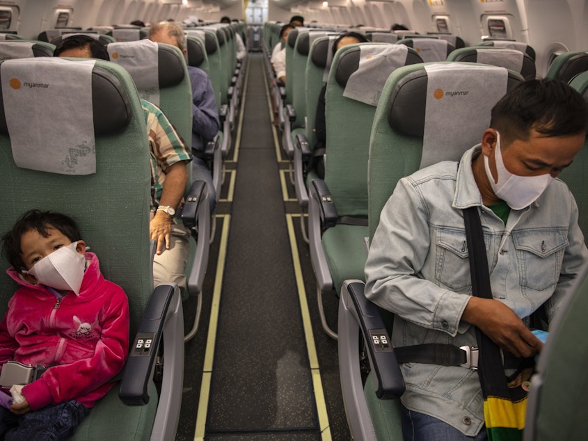 caption: Passengers wear masks on a Myanmar National airlines flight out of Yangon. Many airlines now require passengers to don masks.