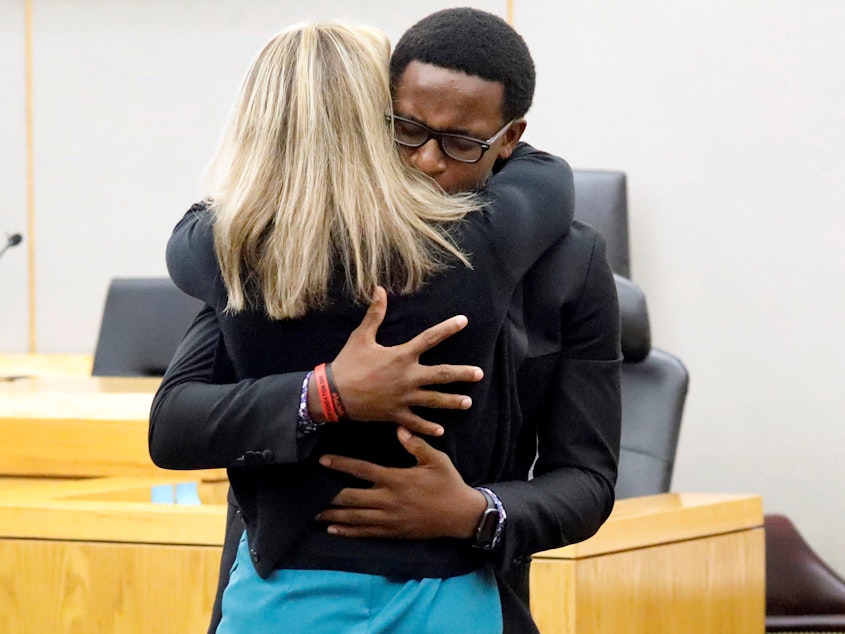 caption: Brandt Jean, Botham Jean's younger brother, hugs former Dallas police officer Amber Guyger in court after saying he forgives her for killing his brother. Guyger received a 10-year prison sentence for murder.