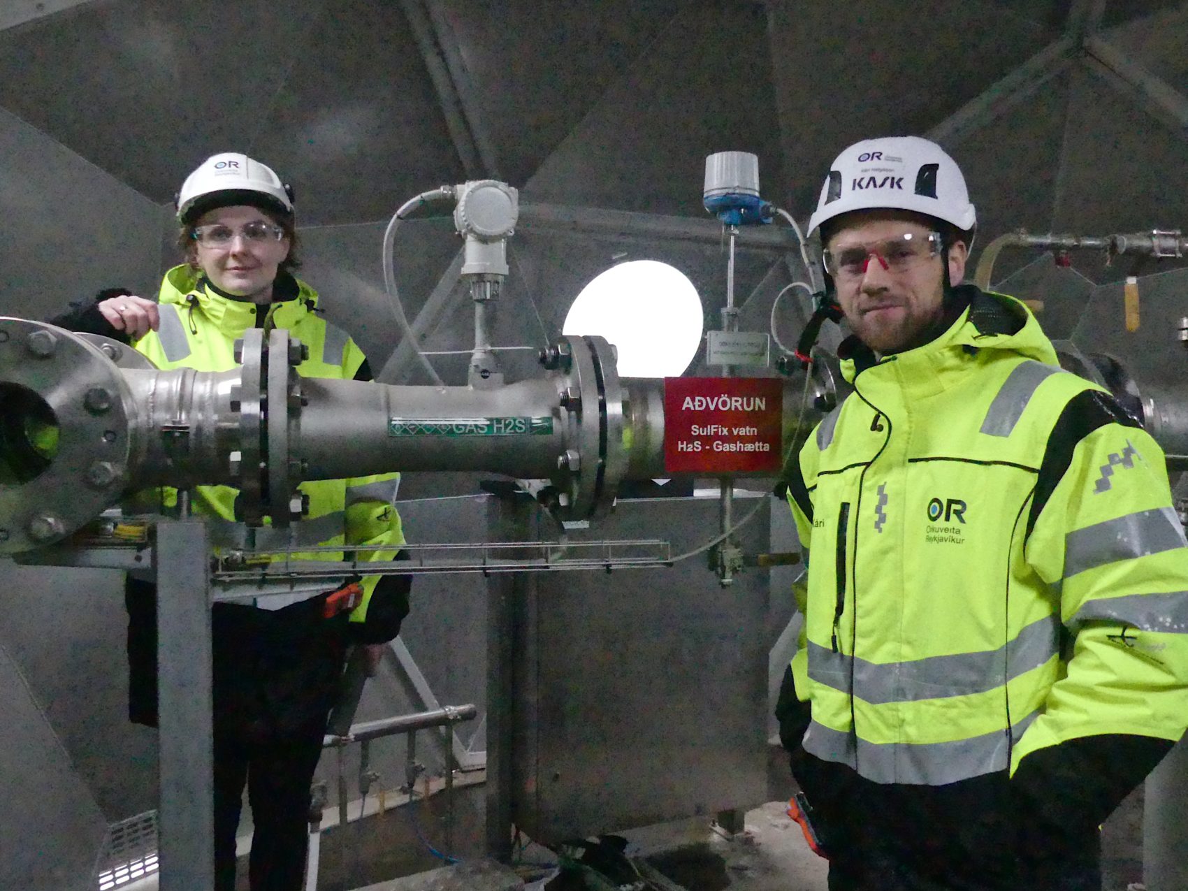 caption: Two scientists at the injection well indoors. (Karyn Miller-Medzon/Here & Now)