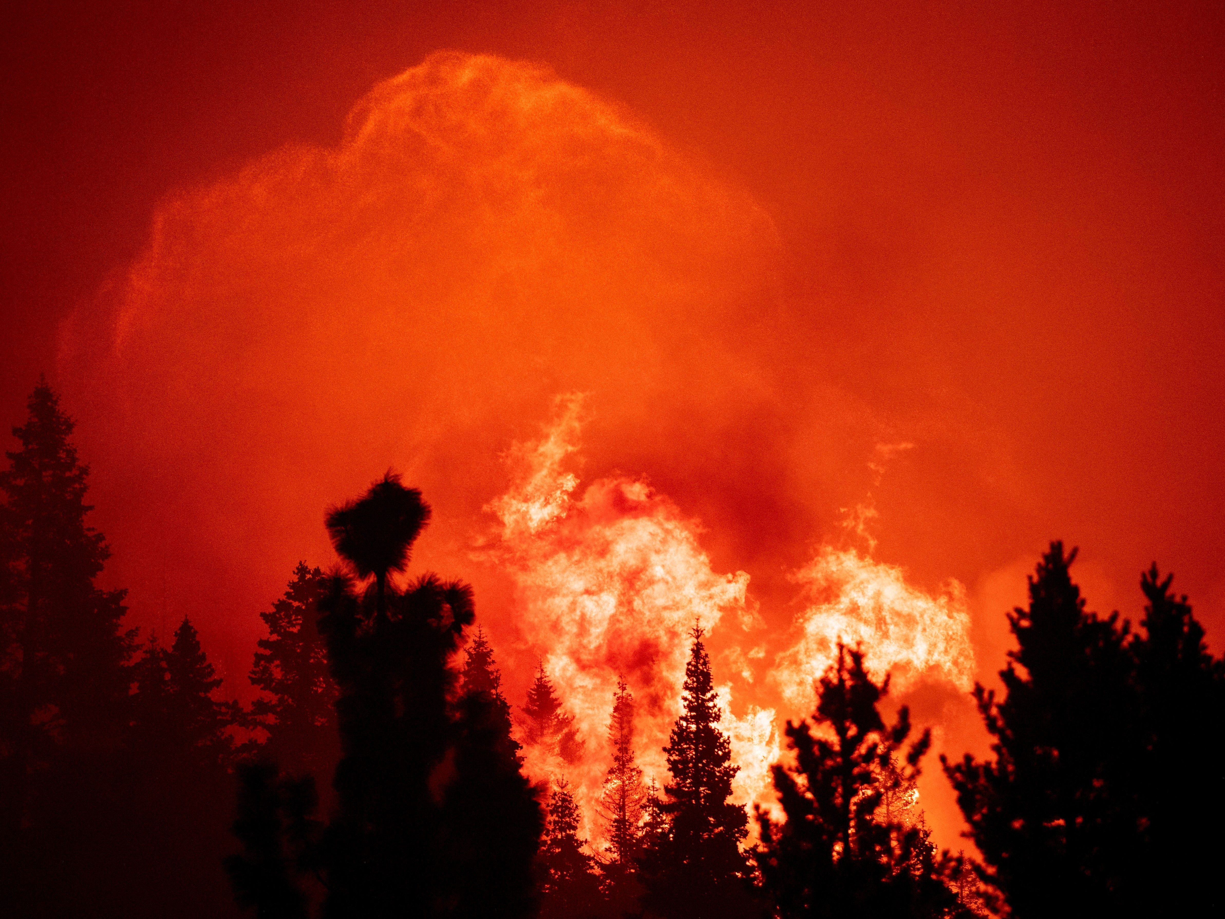 caption: Flames and embers tower into the sky as firefighters work to protect homes from the Caldor fire in Twin Bridges, California on August 29. A father and son are accused of "reckless arson" in connection with the burn, which scorched more than 220,000 acres this fall.