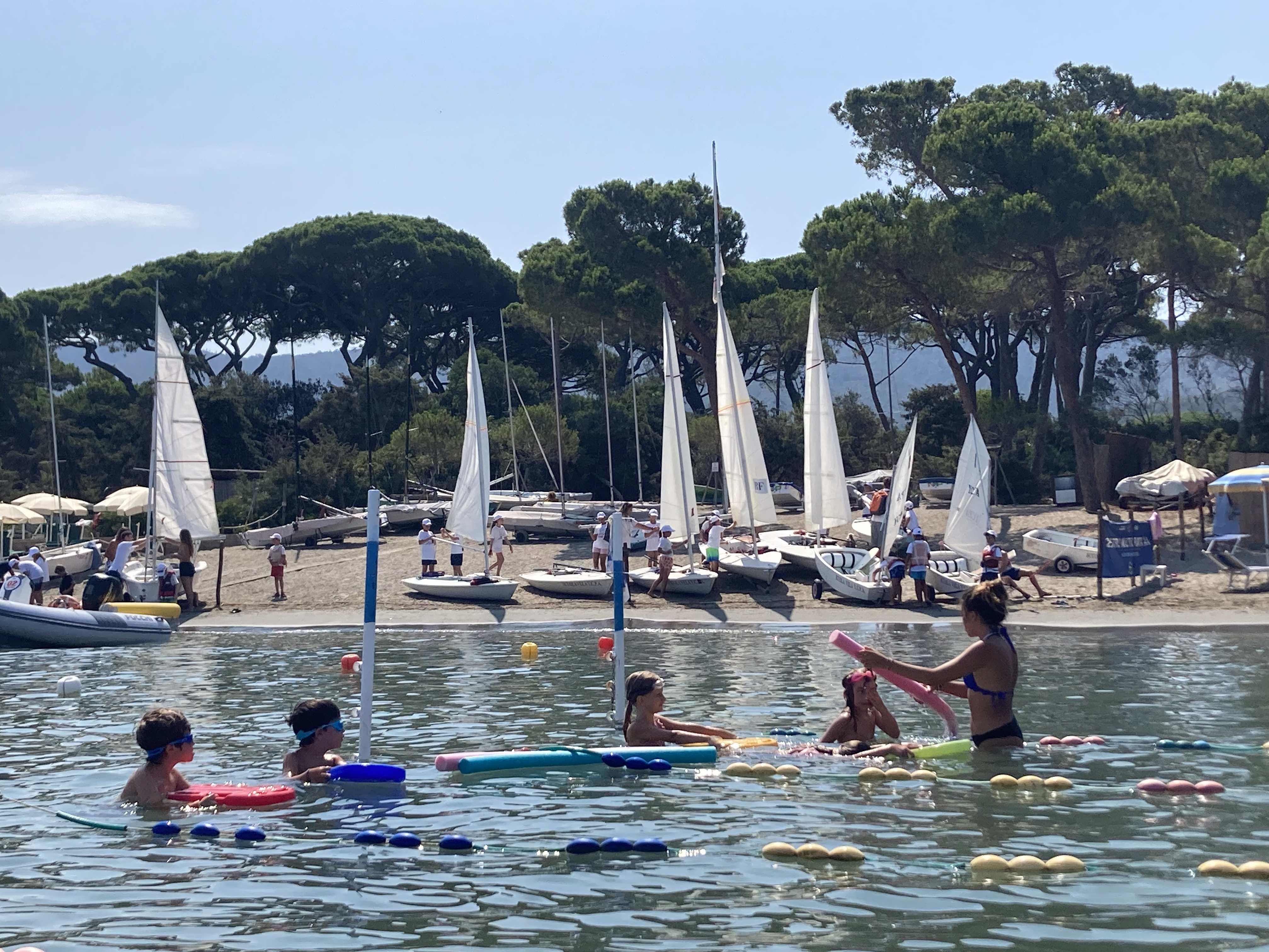 caption: Swimming and sailing classes are just a few of the sports on offer to families who vacation in Punta Ala. Families return year after year to give their children a break in nature and let them reunite with friends they only see in the summer.