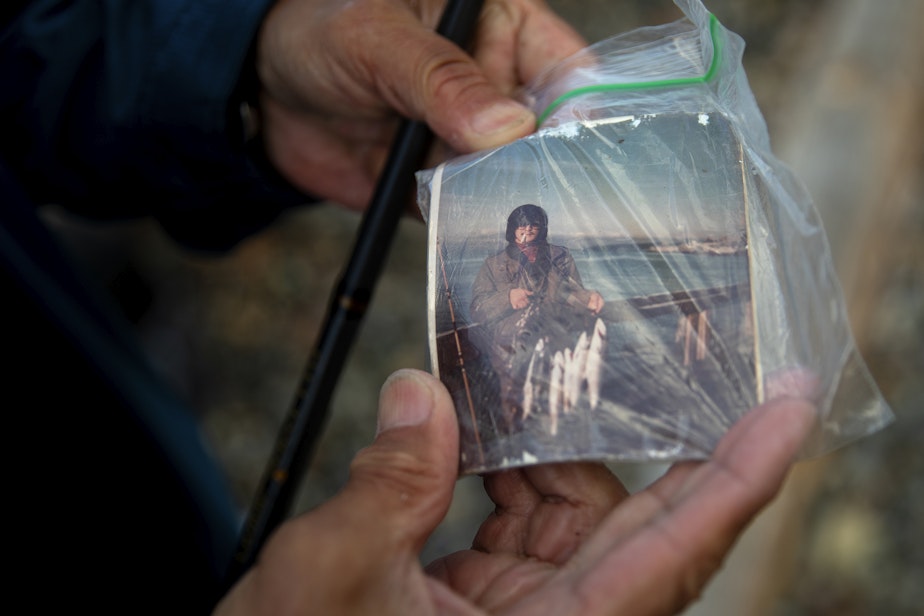 caption: Fisherman Tom Molinas holds an image of himself fishing at Pier 52 in Seattle in the early 90s, when he was 22. 