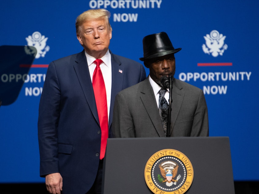 caption: President Trump looks on as Tony Rankins, who works in a so-called Opportunity Zone, addresses a crowd during a speech Friday in Charlotte, N.C., aimed squarely at appealing to African American voters.