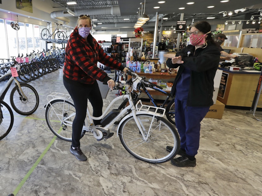 caption: Store manager Josh Hayden, left to right, talks with Kay Amey and Jackie Gee about a new bicycle at Eddy's Bike Shop on Tuesday in Willoughby Hills, Ohio. Bike shops in most states were exempt from shutdown orders and sales have been up.