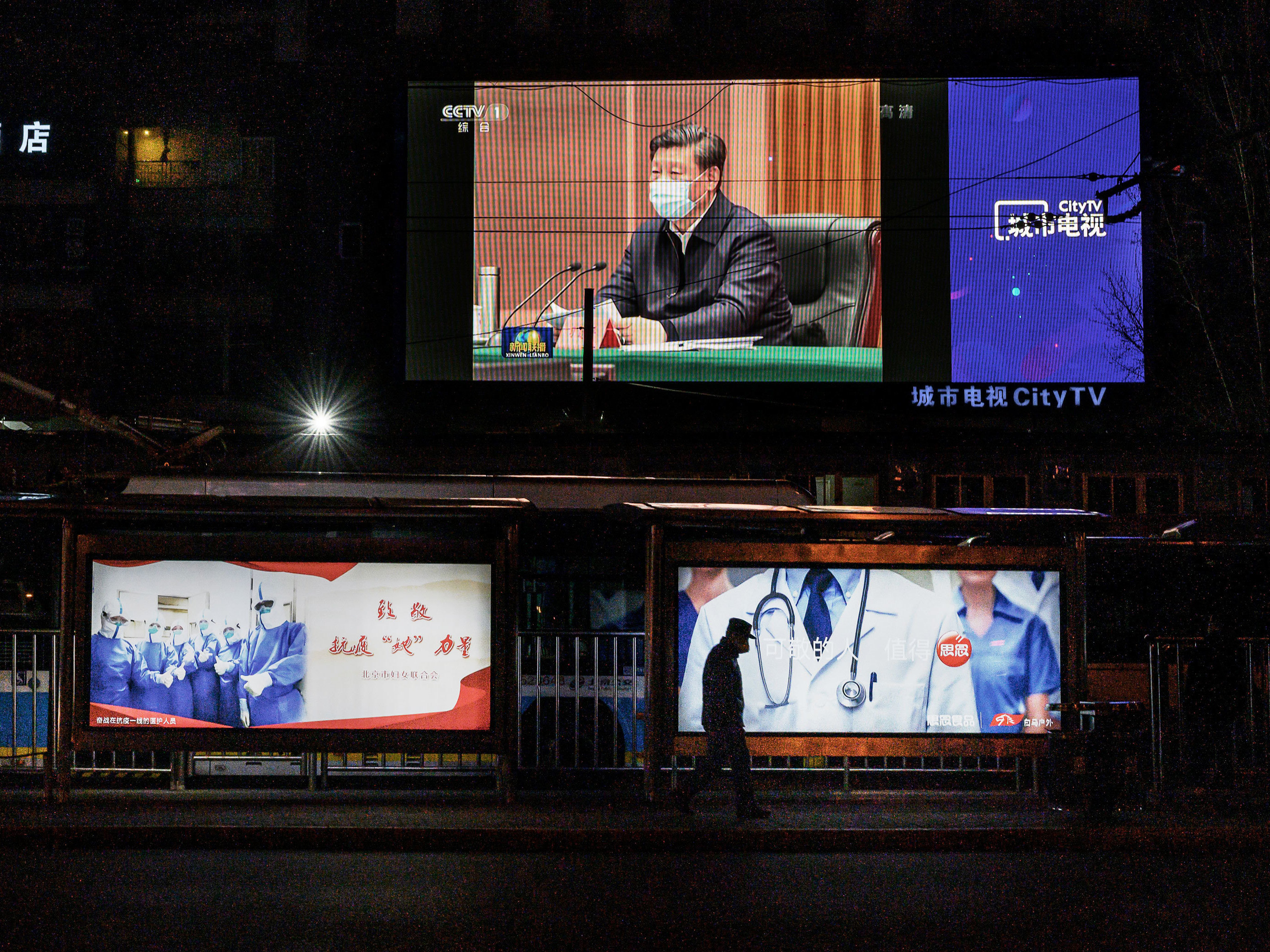 caption: A large screen broadcasting an evening newscast along a Beijing street in March shows Chinese President Xi Jinping wearing a protective mask during his visit to Wuhan earlier in the day.