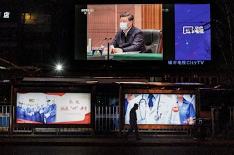 caption: A large screen broadcasting an evening newscast along a Beijing street in March shows Chinese President Xi Jinping wearing a protective mask during his visit to Wuhan earlier in the day.