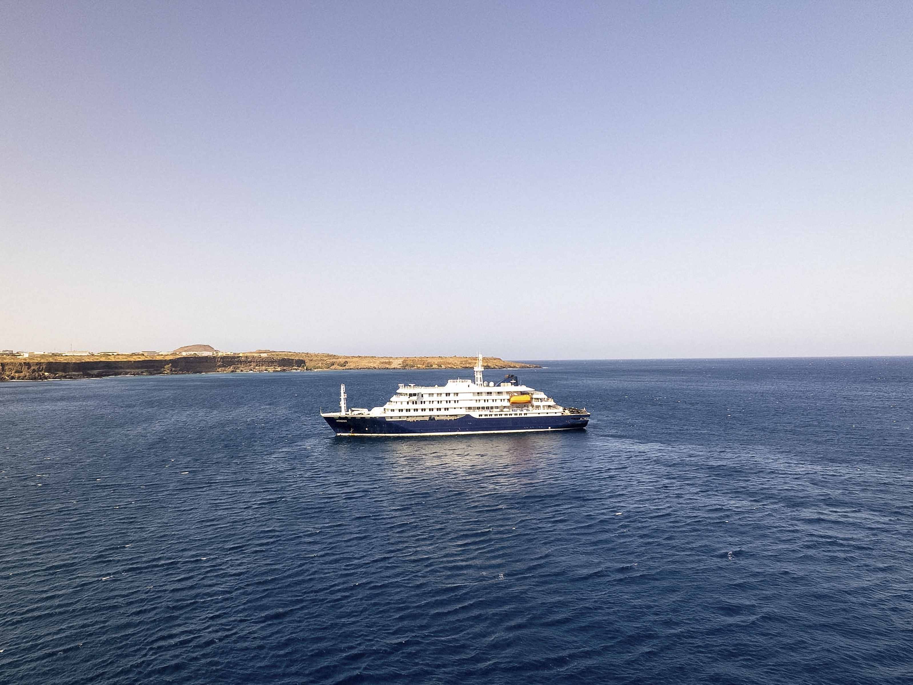 caption: This aerial picture shows a general view of a cruise ship off the port of Praia, the capital of Cape Verde, on Sunday. Three people have died in an outbreak of a dangerous respiratory virus on a cruise ship in the Atlantic Ocean, according to the World Health Organization.