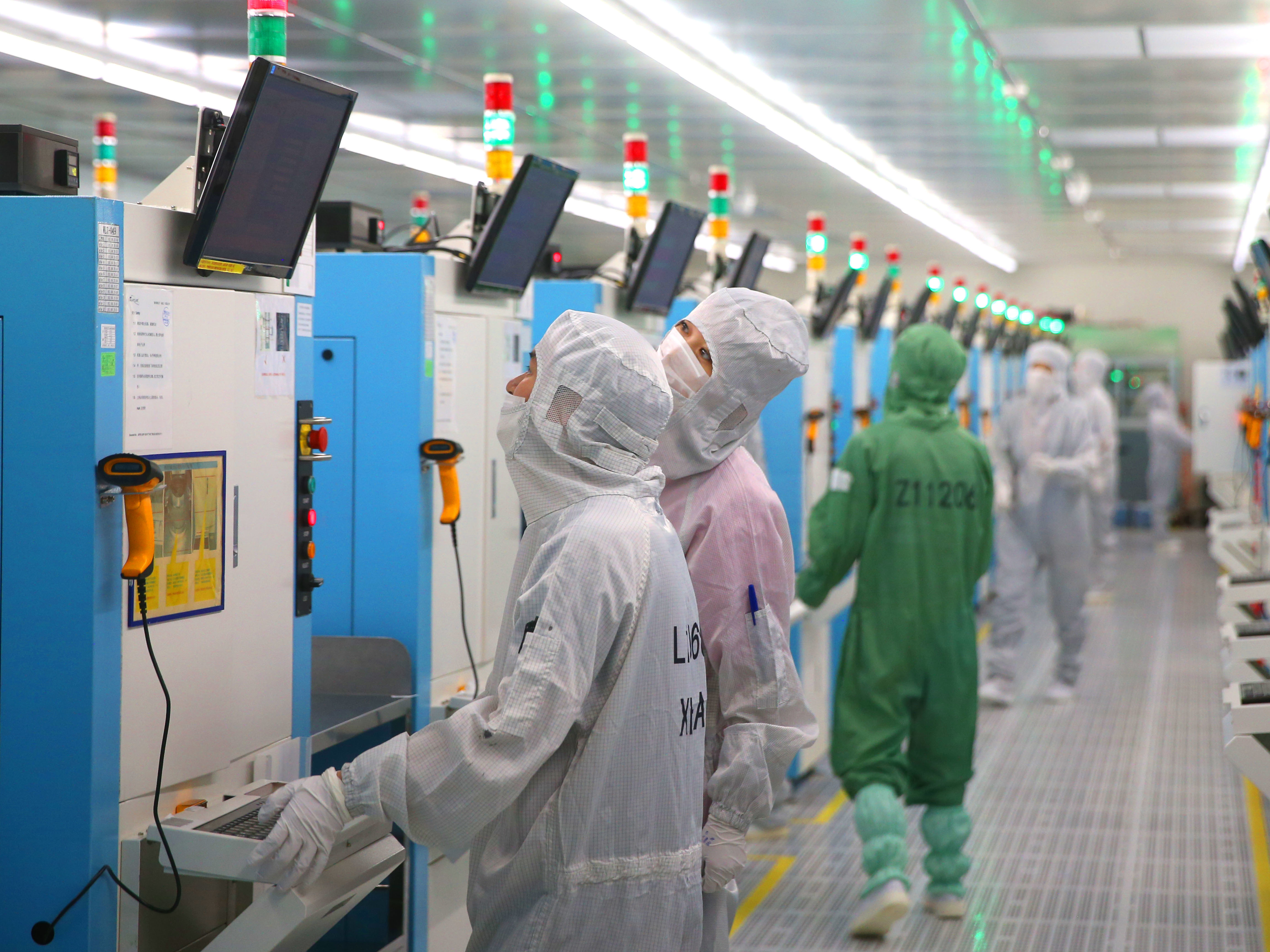 caption: The Senate is expected to approve incentives for U.S. companies to compete with China on technology. Pictured here are employees of a Chinese factory producing silicon wafers this week.