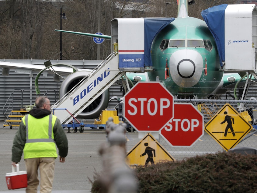 caption: A Boeing worker walks near a 737 MAX jet in Renton, Wash. 