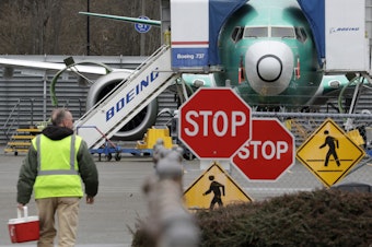 caption: A Boeing worker walks near a 737 MAX jet in Renton, Wash. 