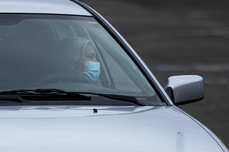 caption: Soledad Colmenares speaks to Father Jose Alvarez during walk and drive through confessions on Friday, April 24, 2020, in the parking lot at Holy Family Roman Catholic Church in White Center. 