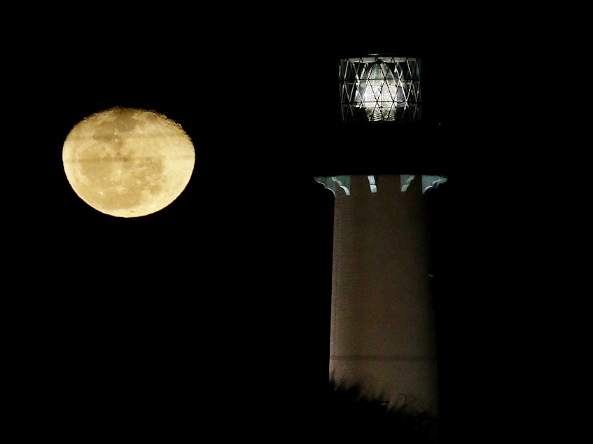 caption: The moon, in its waning gibbous state, rises near the Jupiter Lighthouse in 2013, in Jupiter, Fla. The 108-feet tall, brick structure was first lit in 1860. The lighthouse sits atop a Native American archaeological site, which is at risk from the rising sea level.