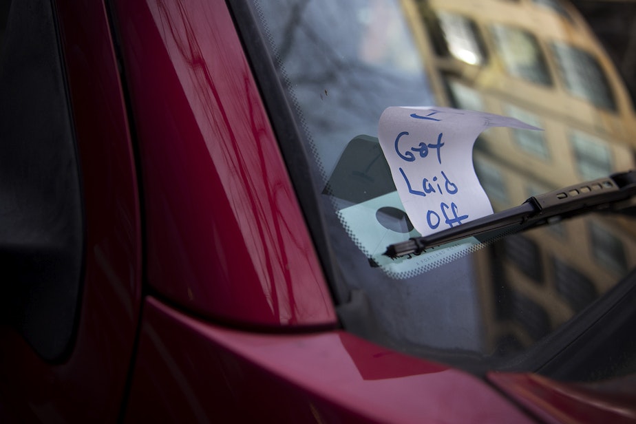 caption: A piece of paper meant to look like a previously issued parking ticket is shown under the windshield wiper of a vehicle with a handwritten note reading 'I got laid off,' on Tuesday, March 17, 2020, on Ballard Avenue Northwest in Seattle. 