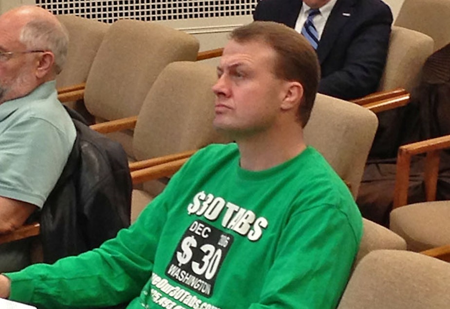 caption: In this file photo, Tim Eyman sits in a legislative committee hearing.