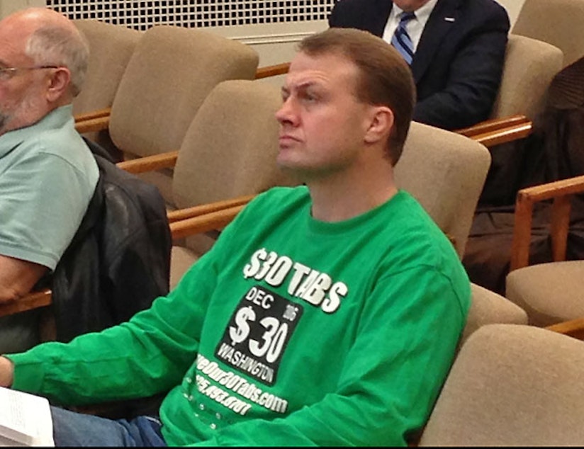 caption: In this file photo, Tim Eyman sits in a legislative committee hearing.