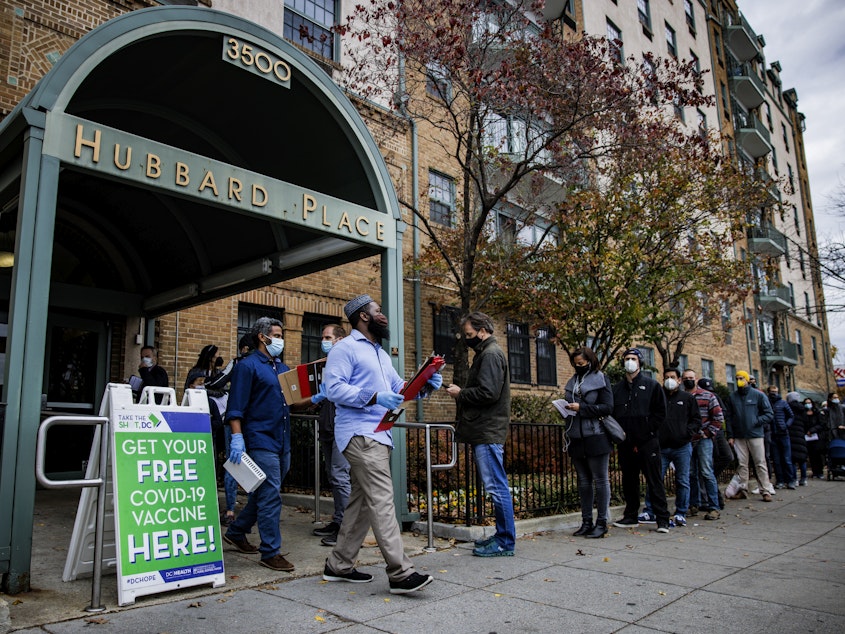 caption: People line up outside a free COVID-19 vaccination site that opened Friday in Washington, D.C. The local health department is stepping up vaccination and booster shots as more cases of the omicron variant are being identified in the United States.