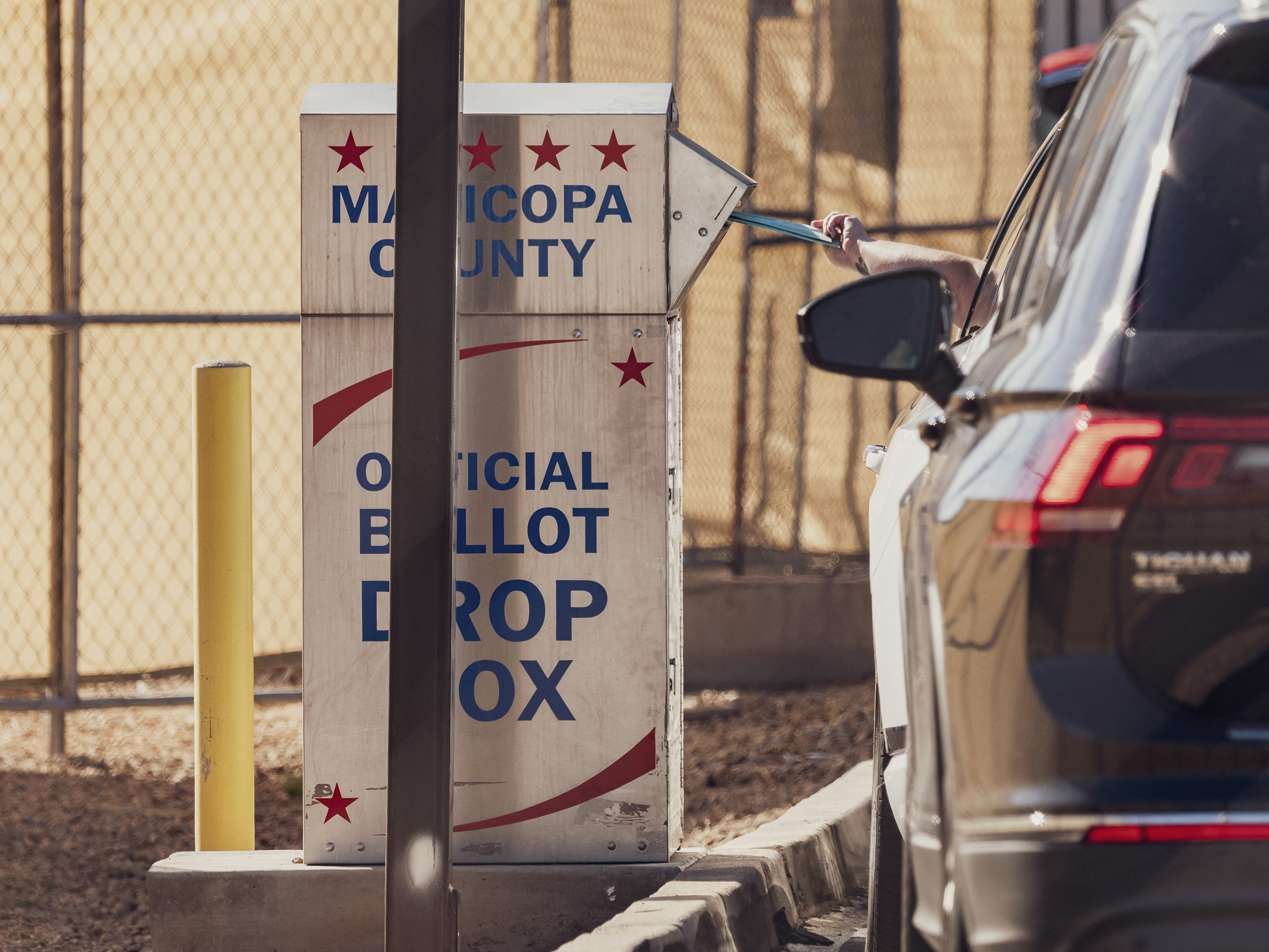 caption: A voter drops a ballot into the drop box at the Maricopa County Tabulation and Election Center in Phoenix on Wednesday.