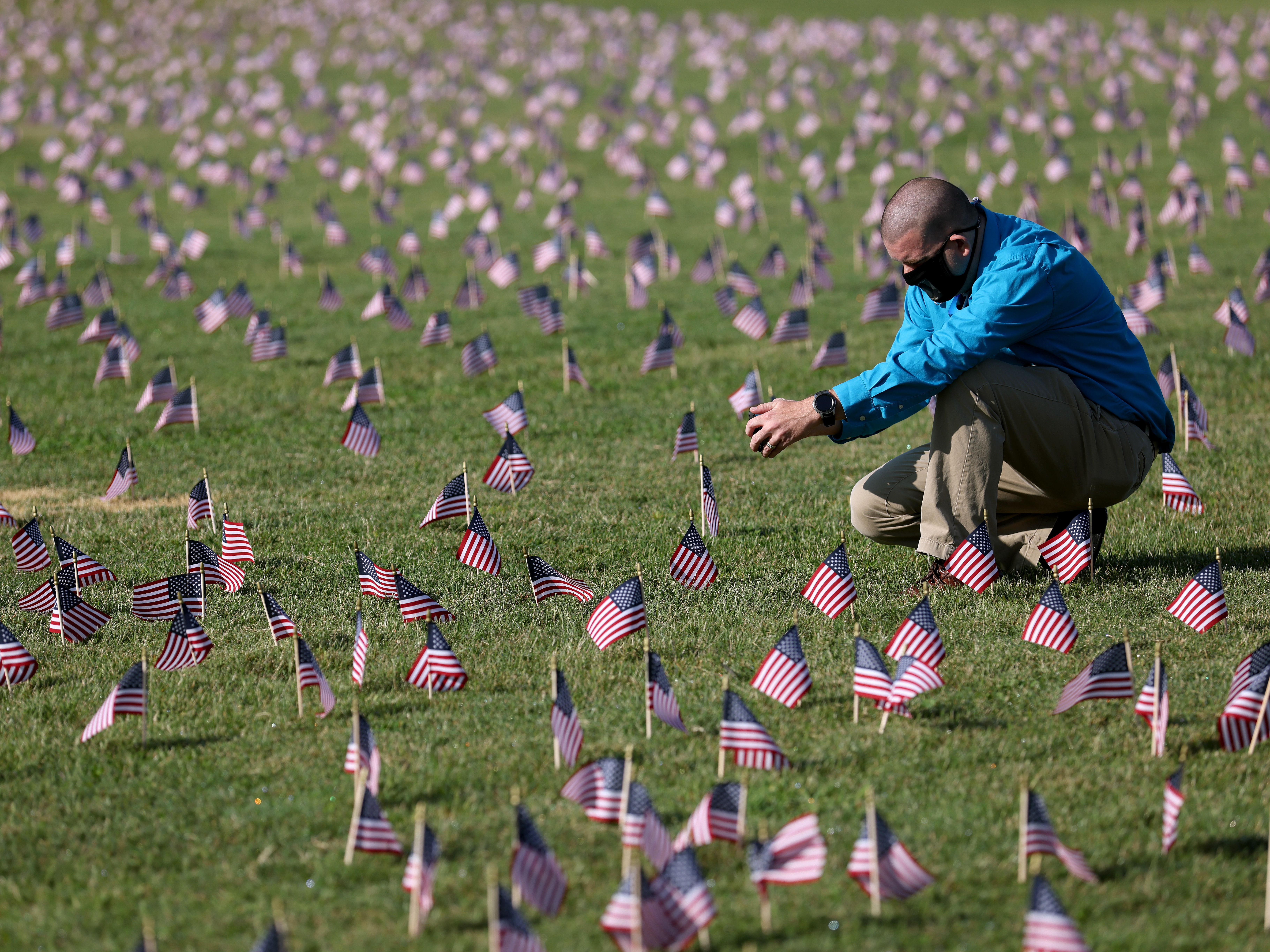caption: The U.S. hit a tragic milestone Tuesday, recording more than 200,000 coronavirus deaths. Here, Chris Duncan, whose 75-year-old mother, Constance, died from COVID-19 on her birthday, visits a COVID Memorial Project installation of 20,000 U.S. flags on the National Mall. The flags are on the grounds of the Washington Monument, facing the White House.