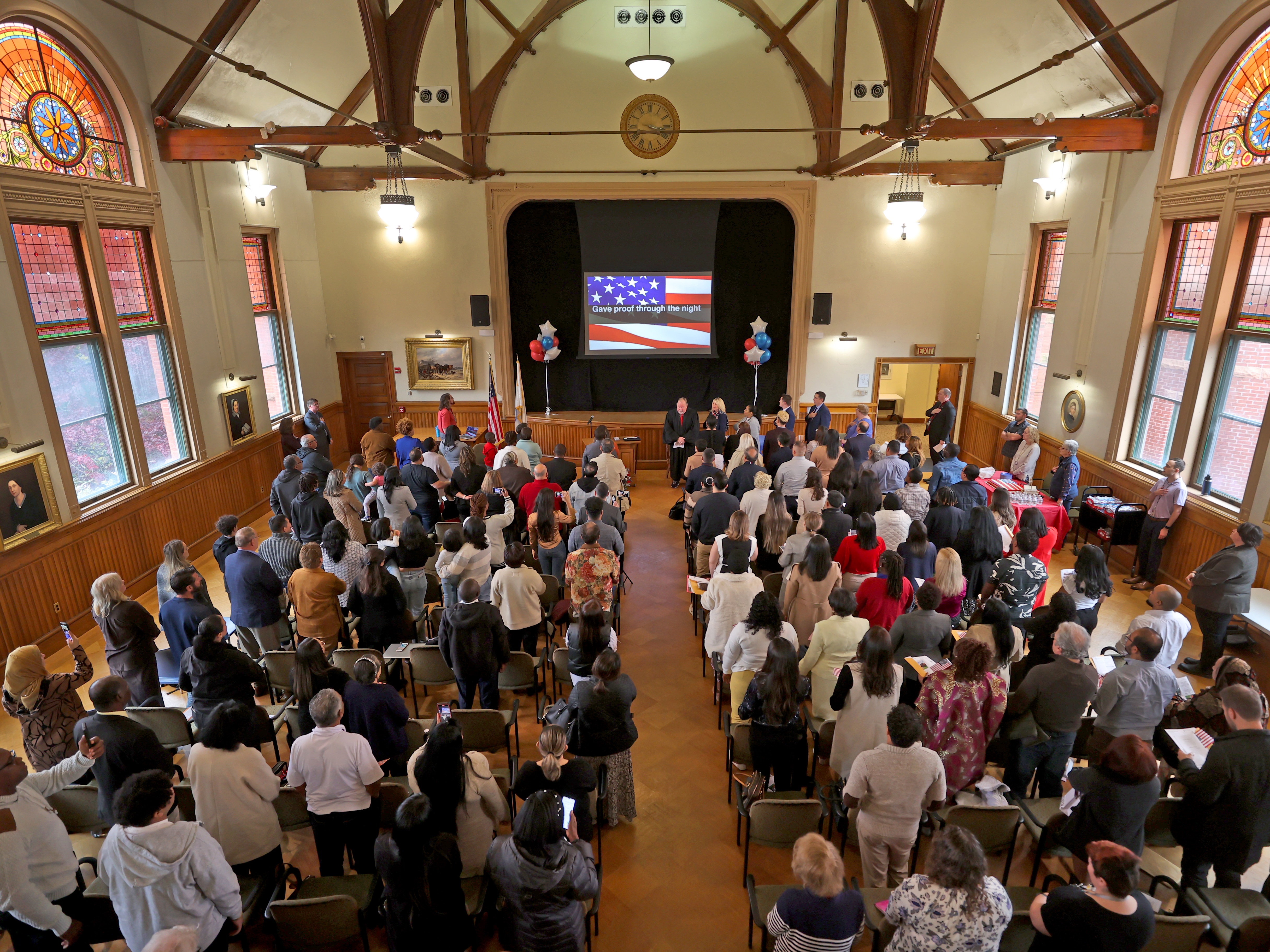 caption: A naturalization ceremony at the Nevins Library in Massachusetts on Oct. 30, 2024.
