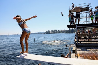 caption: A child jumps from the low dive at Laurelhurst Beach Club in Seattle on Monday, June 28, 2021. The temperature reached 107 degrees at Sea-Tac Airport on this day.
