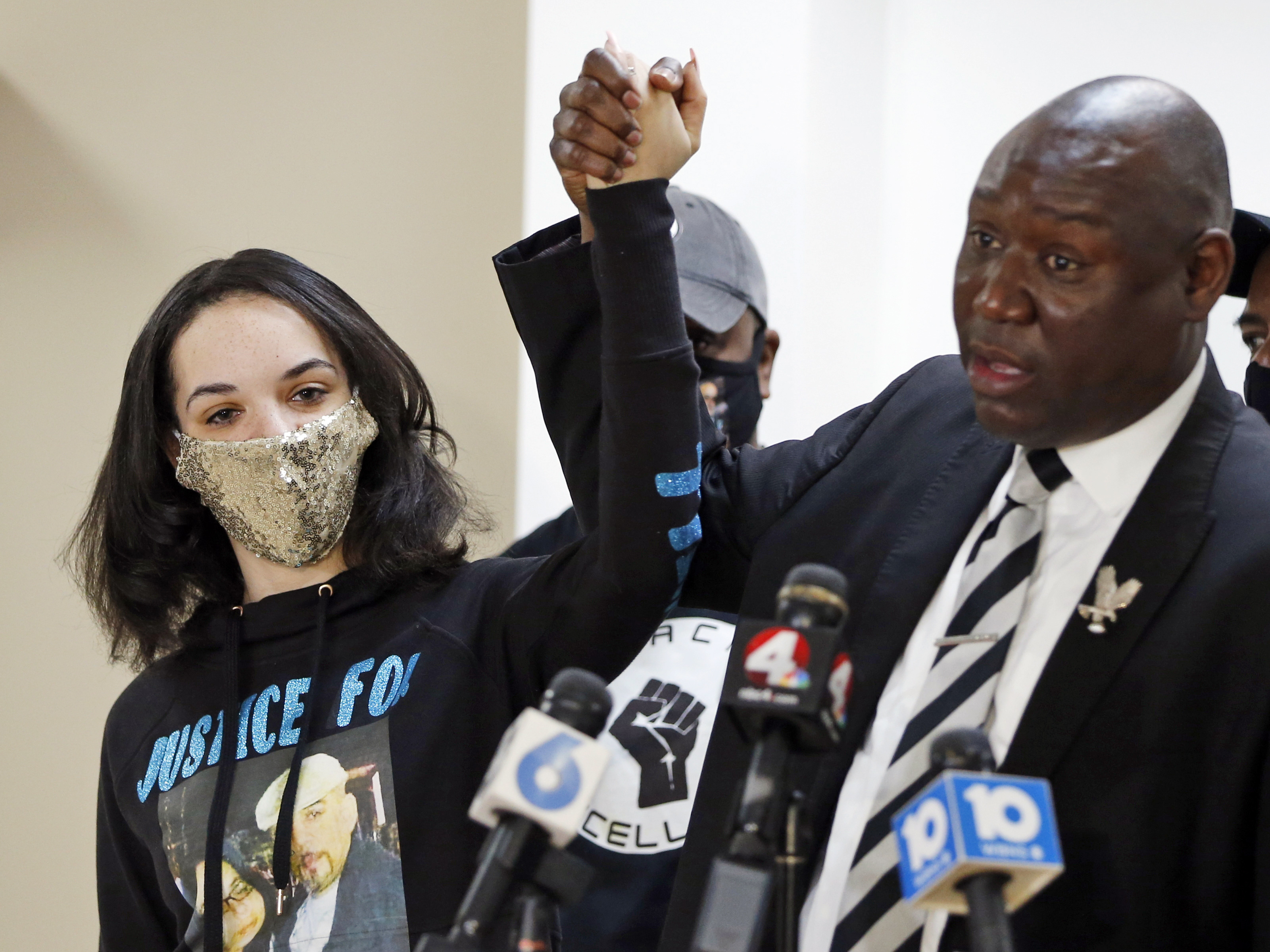 caption: Karissa Hill, daughter of Andre Hill, raises hands with Benjamin Crump, the civil rights attorney representing Hill's family, at a news conference in February after former Columbus police officer Adam Coy was charged with murder in Hill's death.