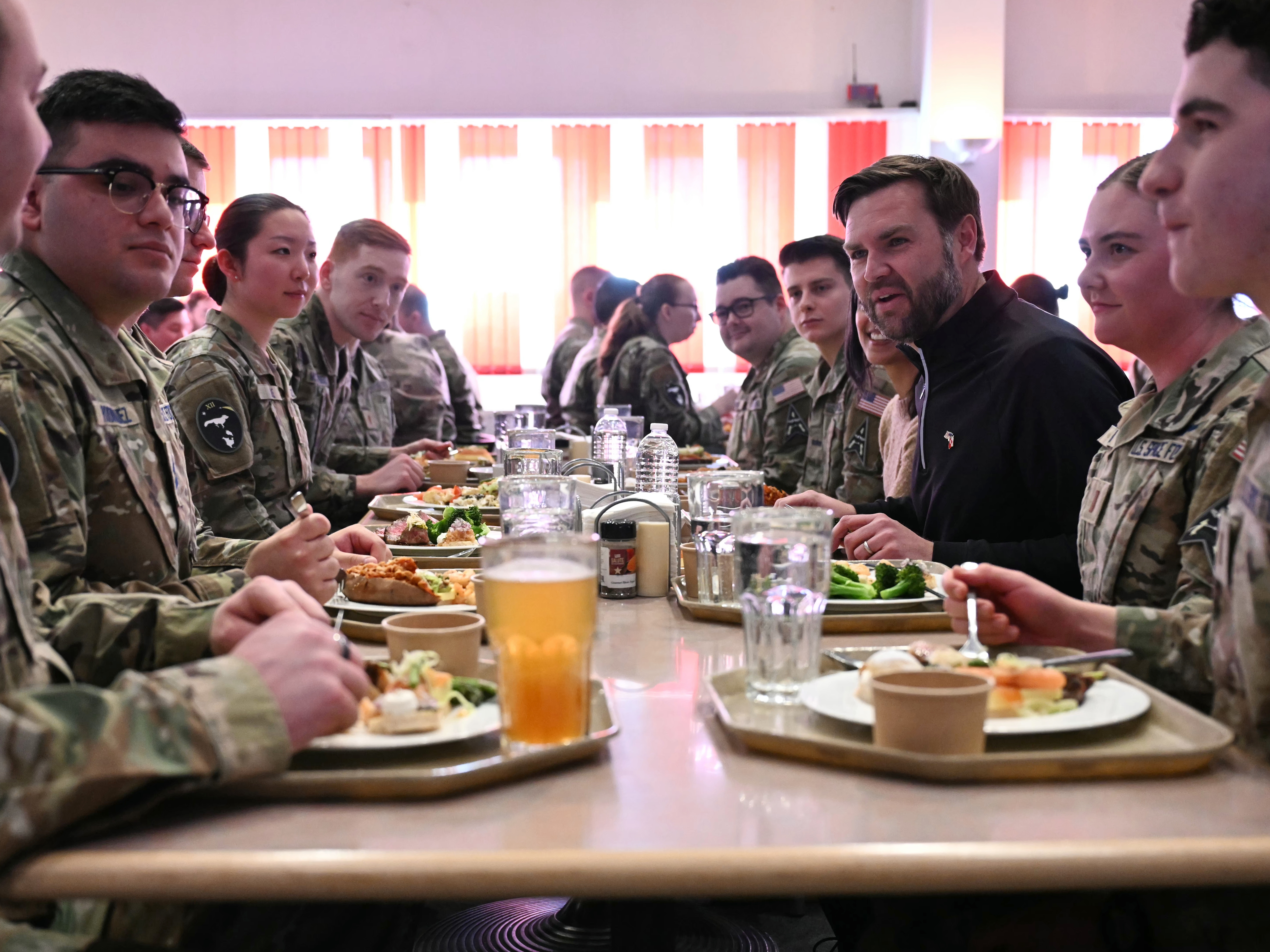 caption: Vice President JD  (at right), seated next to second lady Usha Vance, eats at a table with soldiers at the U.S. military's Pituffik Space Base on March 28 in Pituffik, Greenland.