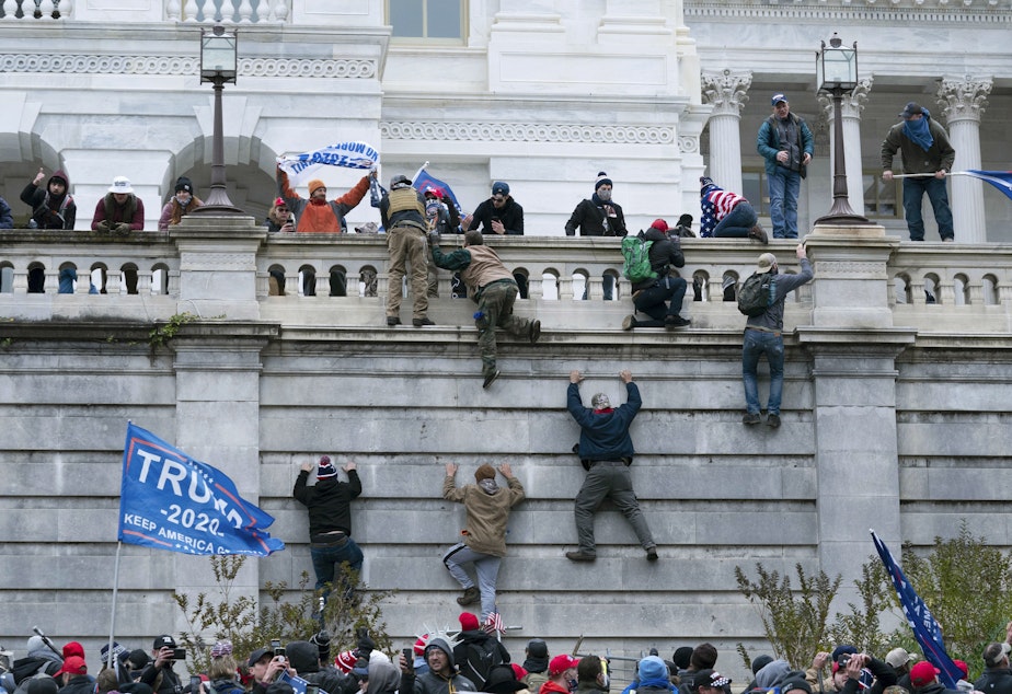 caption: Supporters of President Donald Trump climb the west wall of the the U.S. Capitol on Jan. 6.