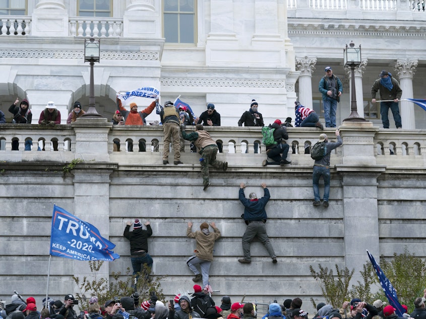 caption: Supporters of President Donald Trump climb the west wall of the the U.S. Capitol on Jan. 6.