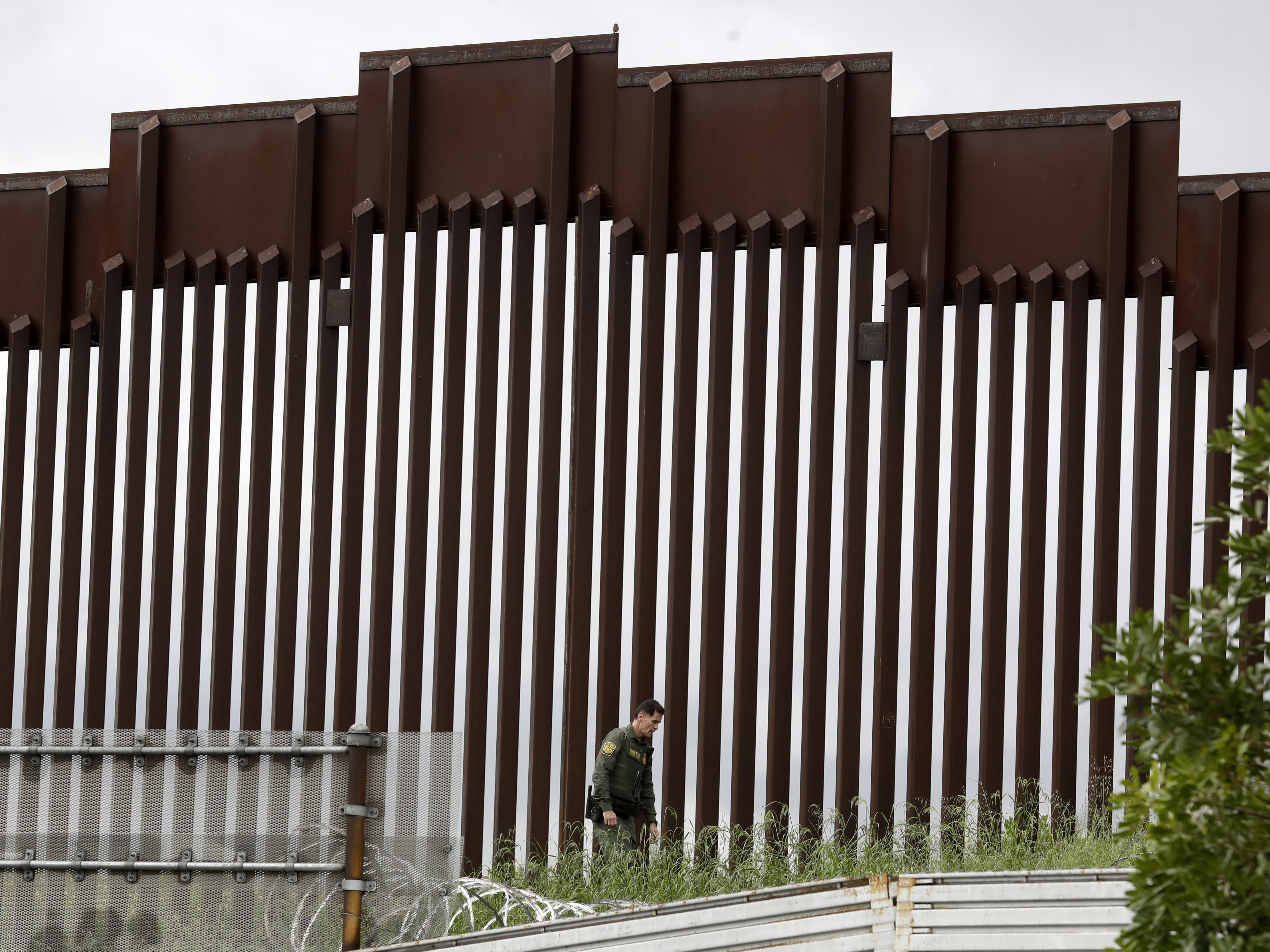 caption: A border patrol agent walked along a border wall separating Tijuana, Mexico, from San Diego earlier this week.